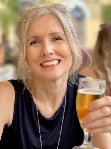 2024 Smiling mature female model holding a drink in casual lifestyle setting