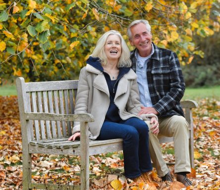 2025 Middle-aged modelling couple seated on garden bench in autumn lifestyle setting