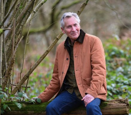 2023 Mature lifestyle model seated outdoors in woodland setting wearing jacket